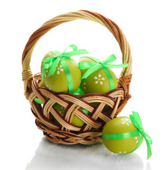 Bright easter eggs with bows in basket, isolated on white