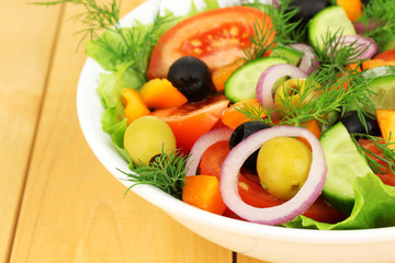 Fresh salad in plate on wooden table