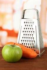 Metal grater and apple, carrot, on bright background