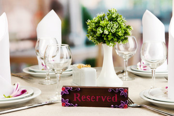 Reserved sign on restaurant table with empty dishes and glasses