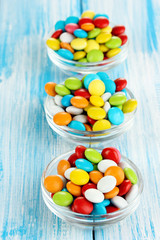 Colorful candies in glass bowls on blue wooden background