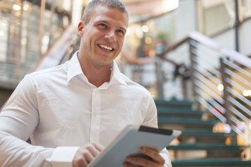 Smiling Man with tablet computer in modern business building