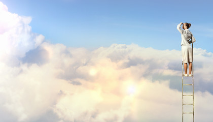 Businesswoman standing on ladder