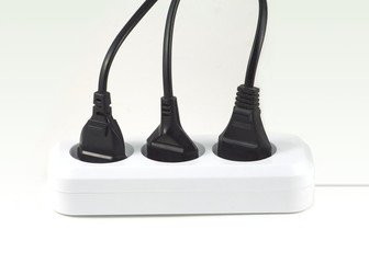 Three black electric plugs in socket isolated on white