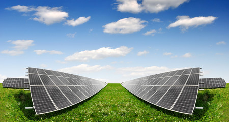 Solar energy panels against blue sky with clouds