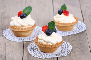 Obraz na płótnie Canvas cakes with cream and berries on wooden background