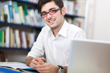 Obraz premium Man researching at the library with a laptop computer