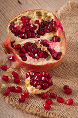 pomegranate seeds on a background of wood and burlap