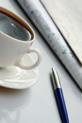 Cup of coffee near newspapers