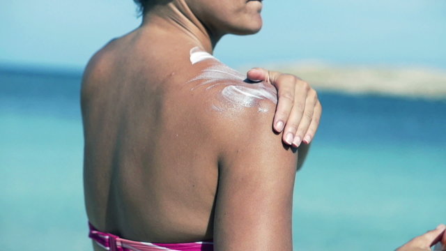 Woman applying sun lotion on her shoulders, slow motion shot at 