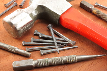 Box nails, hammer, and nail sets arranged on wood back ground