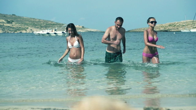Three friends comes out of the sea after swimming, slow motion s