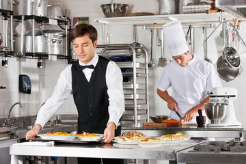 Waiter And Chef Working In Kitchen