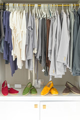 Casual clothes on hangers and shoes at shop.