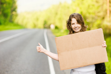 girl on the road waiting for a car with cardboard