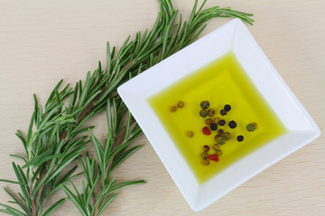 Fresh rosemary herbs and olive oil with pepper on wooden board