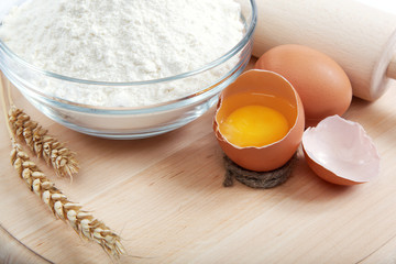 Flour with raw eggs for making dough on the wooden board.