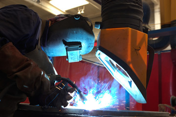 welder with protective equipment and smoke rising