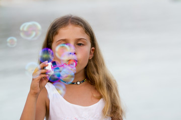 Summer joy - lovely girl blowing soap bubbles