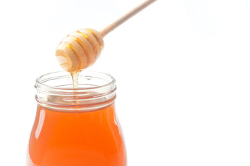 Jar of honey with wooden drizzler isolated on white background