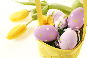 jaja wielkanocne w koszyku na białym tle i tulipany