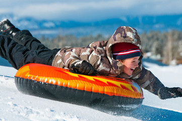 Happy boy riding a tube in snow