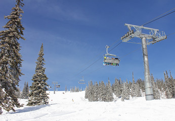 six snowboarders ride the chair lift in a forest