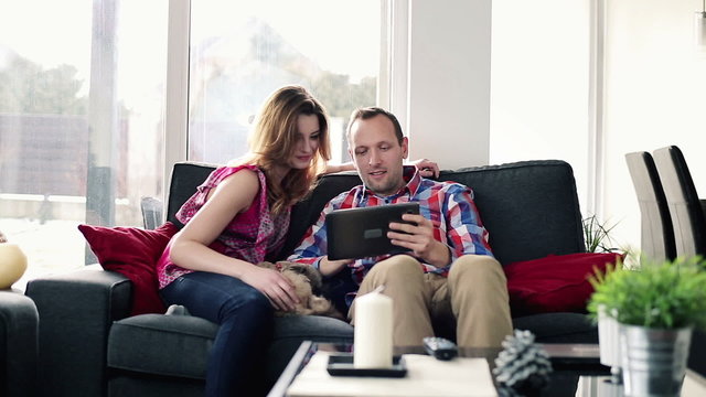 Happy couple with tablet computer on sofa