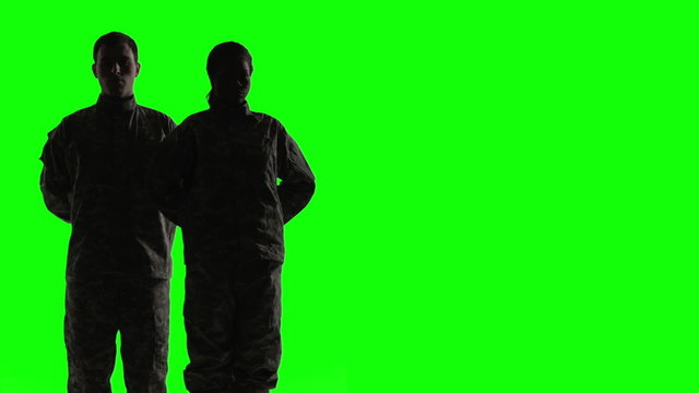 Soldiers silhouette in front of green screen.