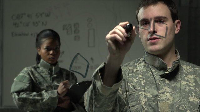 Soldier strategizing with fellow soldier using a board