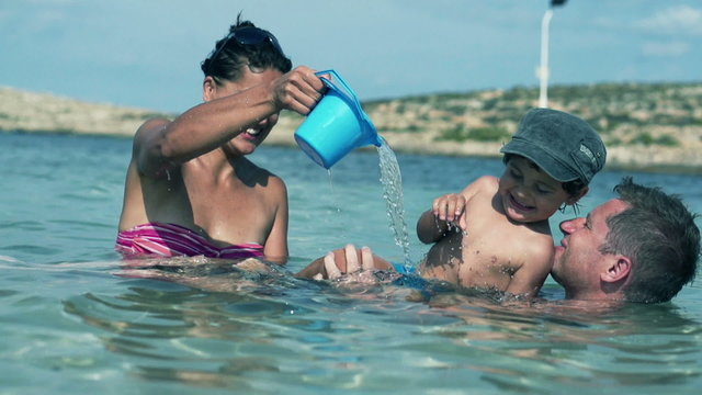 Happy family having fun in the sea, slow motion shot at 240fps
