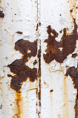 Close up of white paint pealing off of metal with rust stains