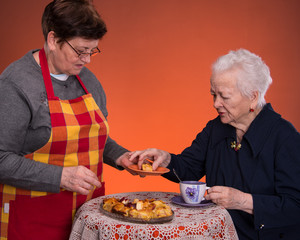 Mother and daughter having tea with apple pie