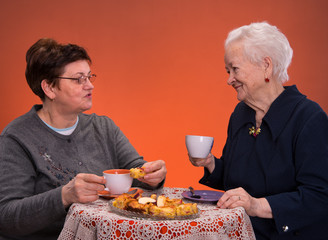 Mother and daughter having tea with apple pie