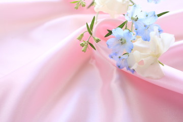 close up of elegant blue Delphinium and sweetpea on pink silk