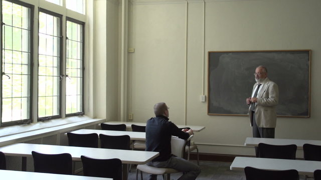 Student and professor talking in a classroom, wide shot