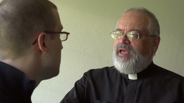 Priest talking with parishioner in a church, close up
