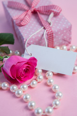 Pink rose with gift and string of pearls with blank tag