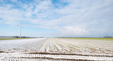 Wind turbine in a snowy field in sunlight