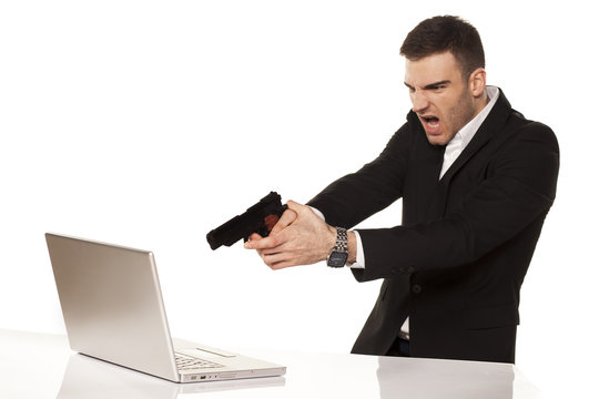 young businessman destroying his laptop using guns