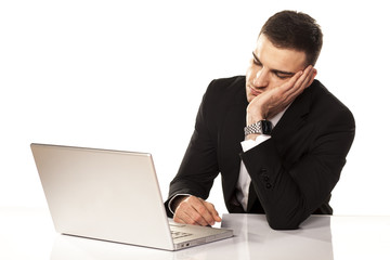 Young businessman has fallen asleep on his arm behind his laptop