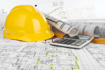 Yellow helmet, calculator, level and project drawings