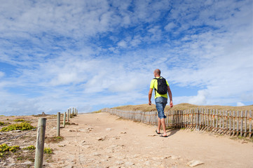 Young man walking in the dunes on a summer day