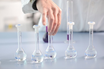 Mens hand holding one of the chemical flasks in laboratory