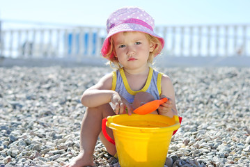 little girl playing on the beach in the summer