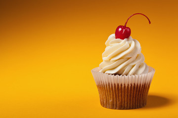 cupcake with red cherry isolated on orange background with copys