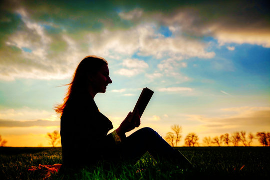 Teen girl reading book outdoors