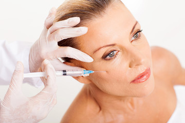 doctor giving mid age woman face lifting injection