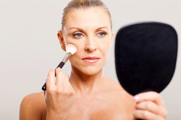 middle aged woman applying makeup