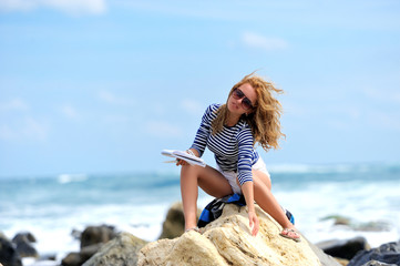Young woman sitting on the stone on the seashore